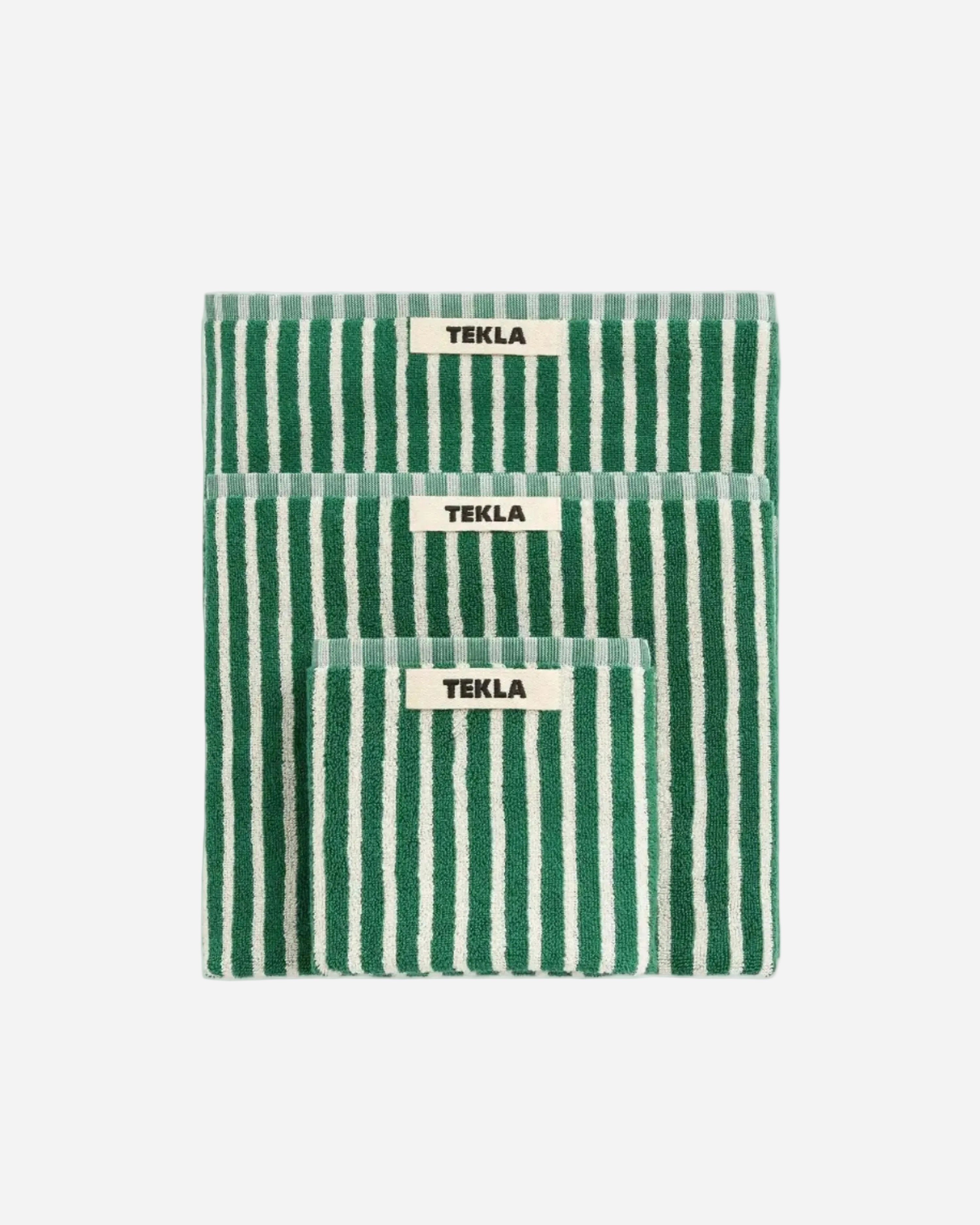 Green and white striped towel with 'Tekla' label on a light gray background